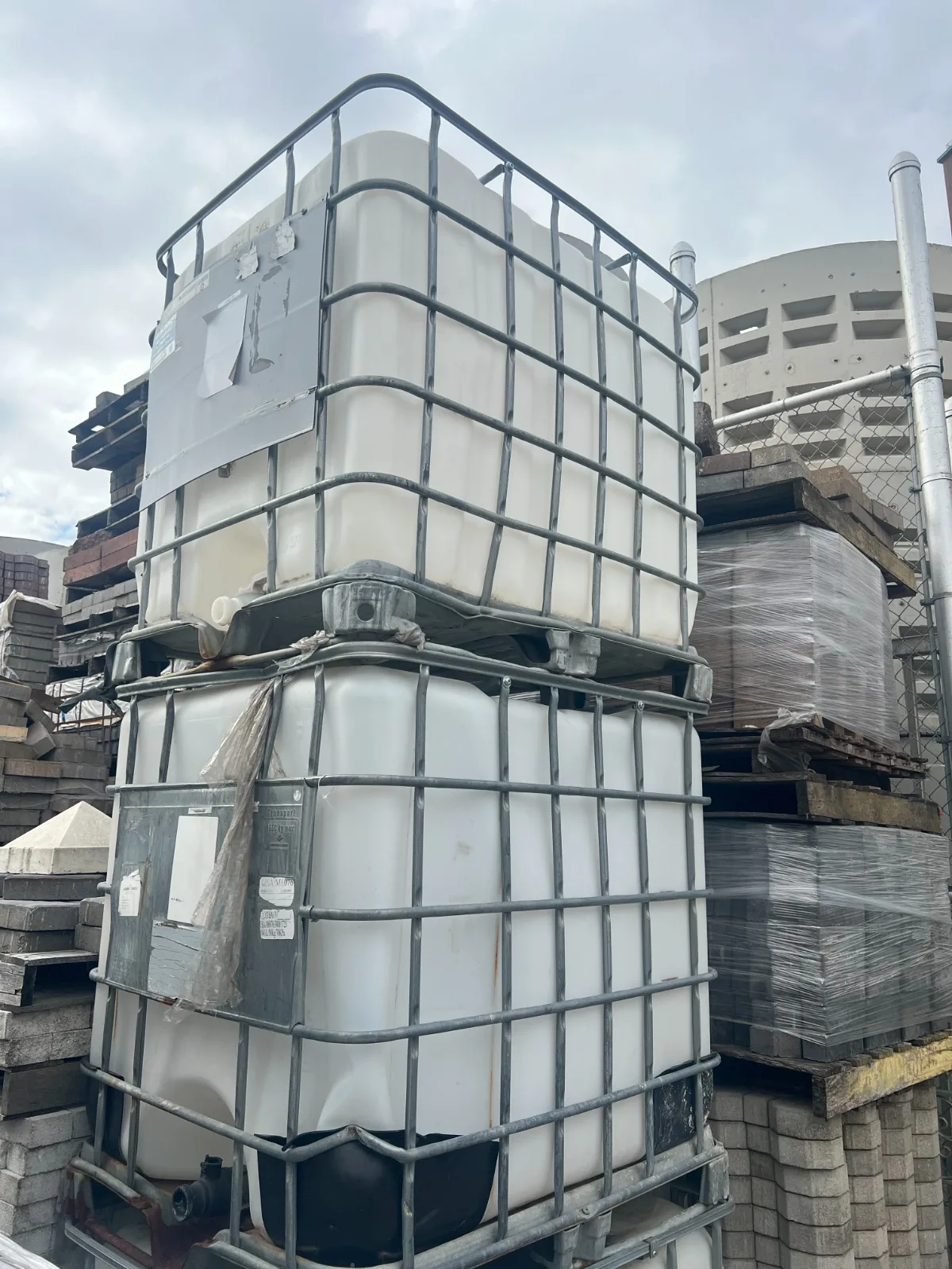 Used IBC totes stacked in a wholesale yard — used buckets wholesale